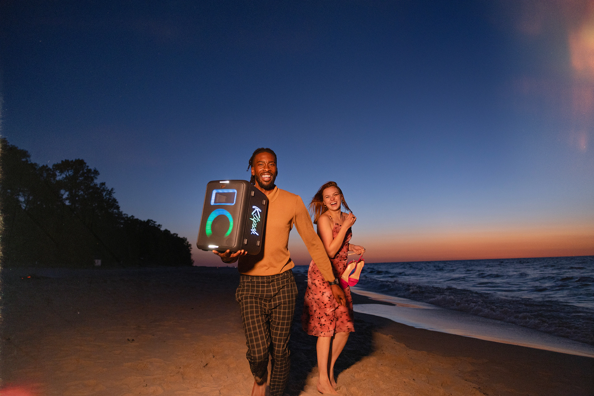 Klipsch Party Speakers Vibe friends running on the beach at sunset with party speaker playing music 2000x1334